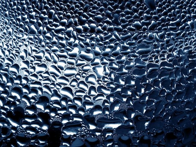 Glass with raindrops on blue tone background