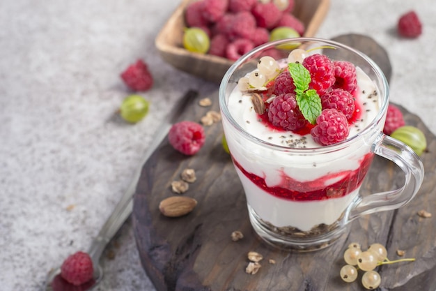 Glass with raspberries granola and yogurt arranged in layers