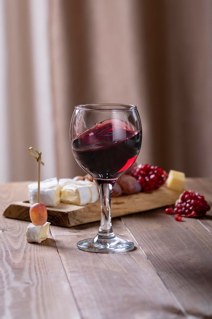 A glass with red wine a board with snacks close up