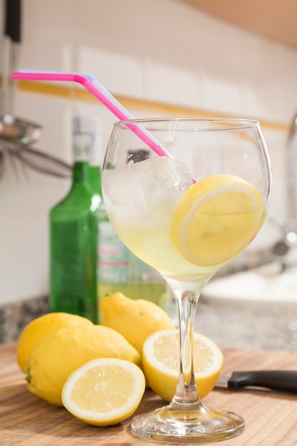 Стакан с ломтиком лимона позади и бутылками Подготовка на кухне