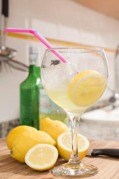 Glass with slice of lemon lemons behind and bottles Preparation in the kitchen