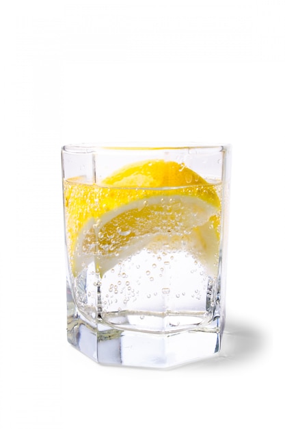 Glass with soda water and lemon slices on white background