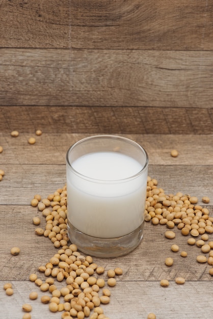 Photo glass with soy milk and soy bean on wooden background