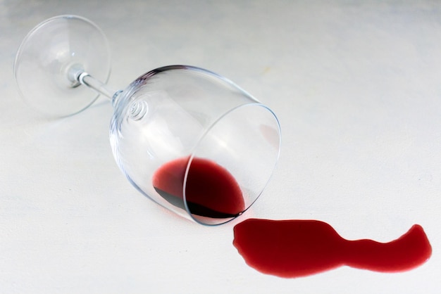 Glass with spilled red wine on a white background Copy space