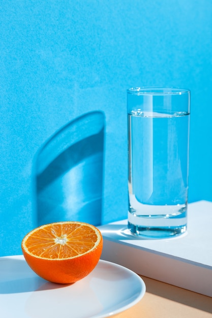 стакан с водой, лимоном и апельсином