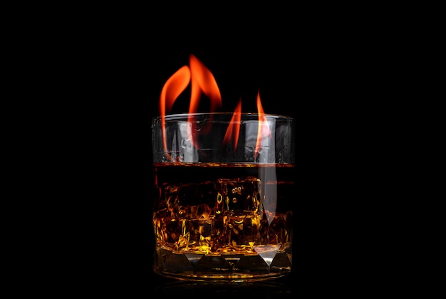 Vetro con whisky di cubetto di ghiaccio e fiamma di fuoco su sfondo nero