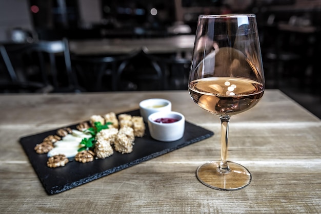 Glass with wine and cheese with sauces on the table