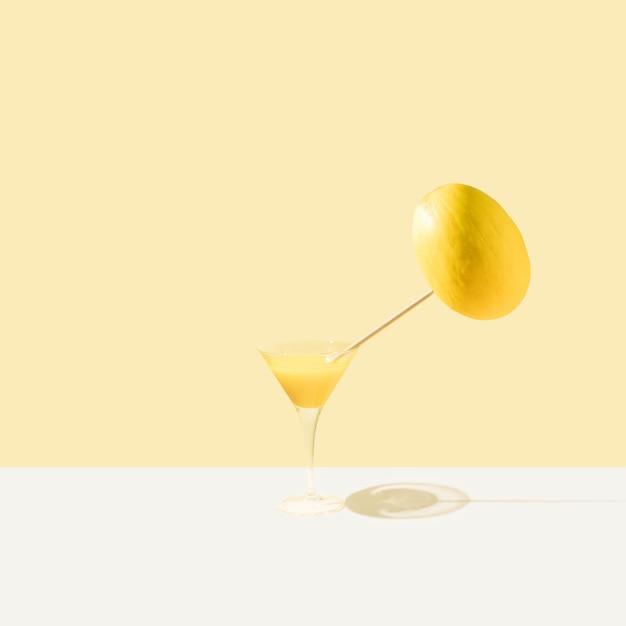 Glass with yellow refreshment drink and vibrant melon on pastel\
beige and white background. minimal food concept. spring or summer\
idea.