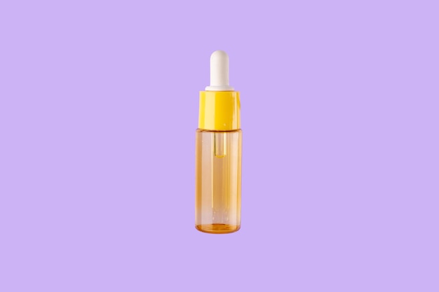 Photo glass yellow bottle with pipette with essential oil on purple background topview aromatic cosmetic
