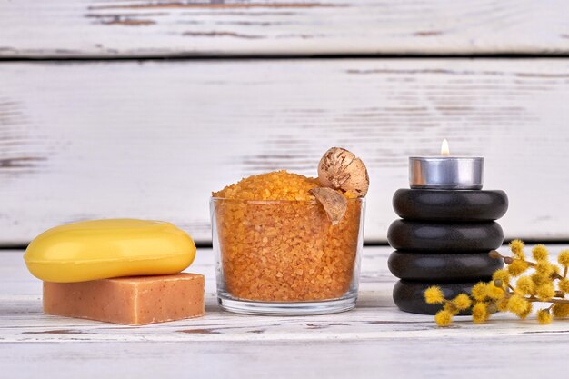 Glass of yellow salt with soap pieces and stack of stones.