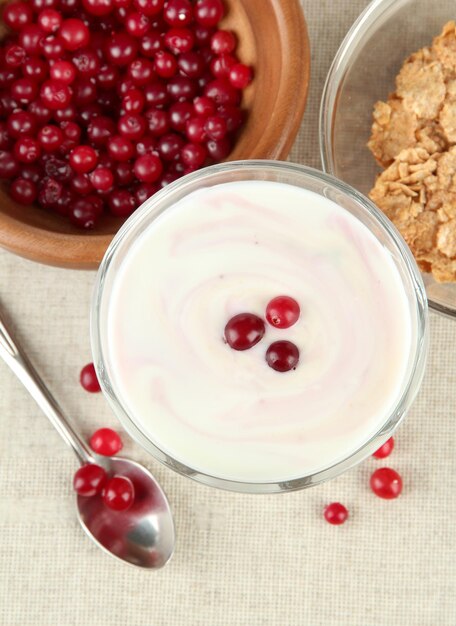 Glass of yoghurt dessert with berries on tablecloth background