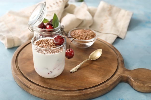 Glass of yogurt with cherry and flax seeds on color