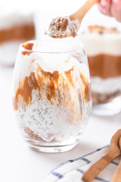 A glass of yogurt with chia, peanut cream, and nuts