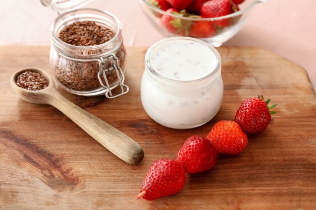 Glass of yogurt with strawberry and flax seeds on board