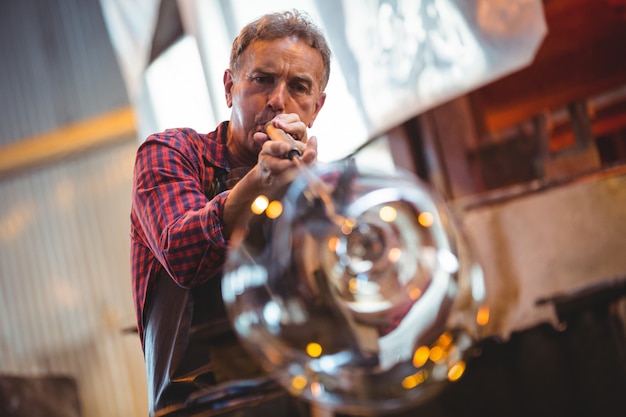 Glassblower shaping a glass on the blowpipe