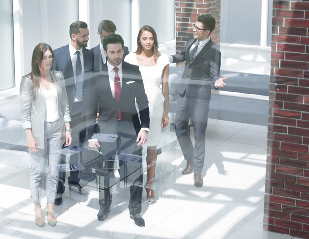 현대적인 밝은 사무실 내부를 걷고 있는 유리 비즈니스 팀 기업인 그룹 뒤에