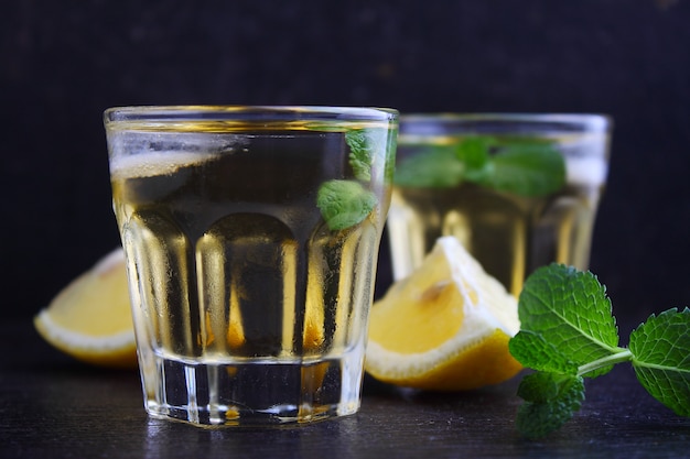 Glasses of alcoholic drink with lemon and mint, Shaker