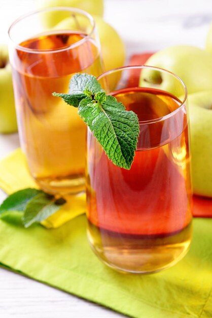 테이블에 과일과 신선한 민트를 넣은 사과 주스 한 잔을 닫습니다.
