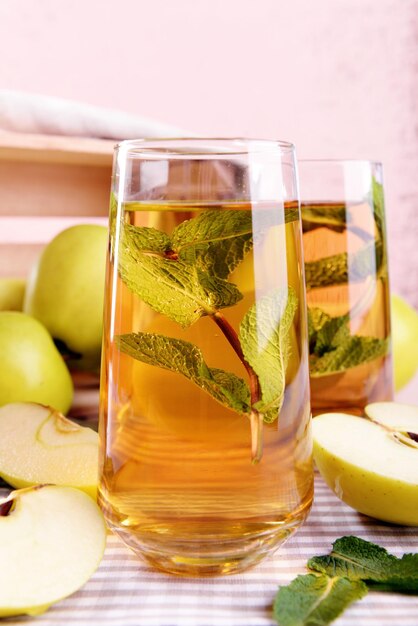 Glasses of apple juice with fruits and fresh mint on table close up