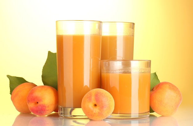 Glasses of apricot juice on yellow