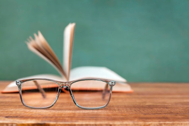 glasses on the background of an open book on a wooden table