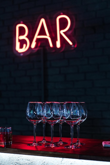 Glasses on bar neon sign background