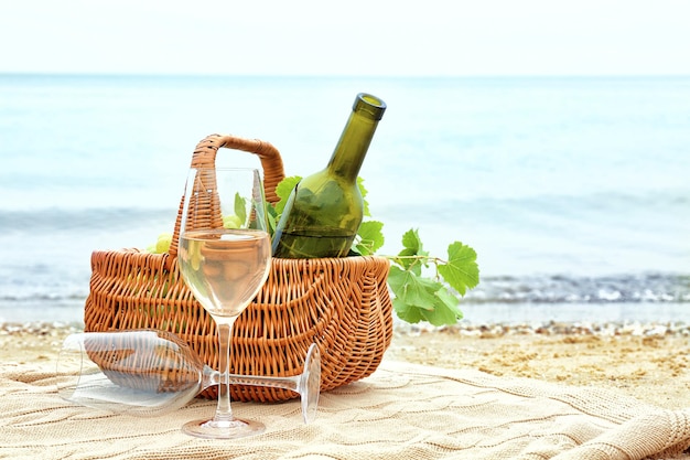 Glasses basket with bottle and fresh grapes on beach