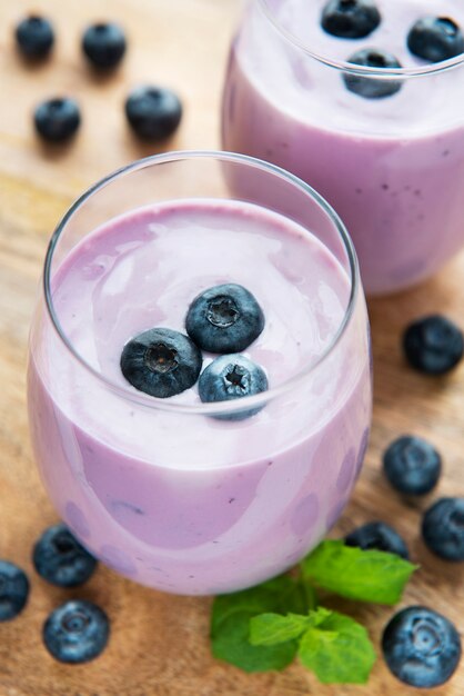 Glasses of blueberry yogurt with blueberries on a wooden background.