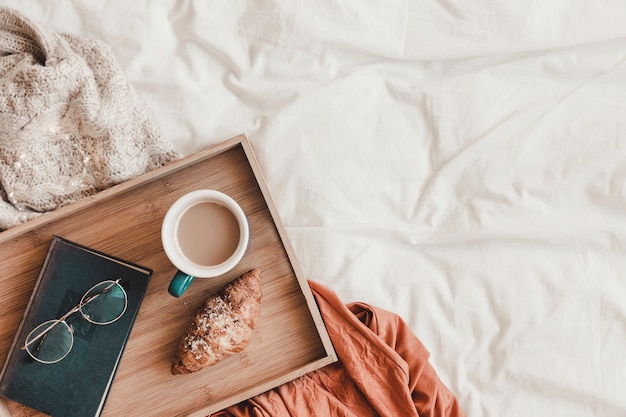 Photo glasses and book near breakfast food on bed