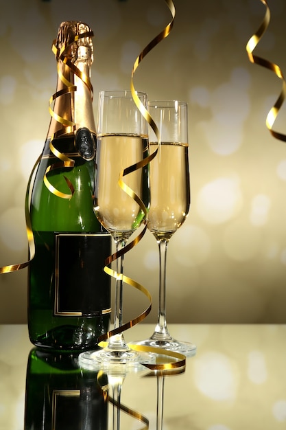 Glasses and bottle of champagne on light background