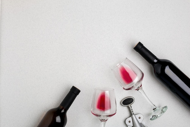 Glasses and bottles of red and white wine on white background from top view