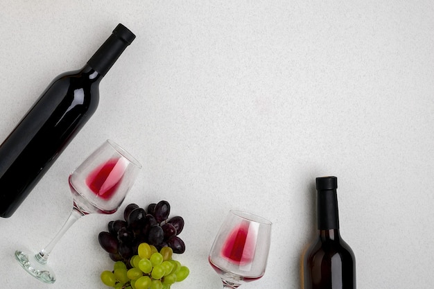 Bicchieri e bottiglie di vino rosso e bianco su sfondo bianco dalla vista dall'alto