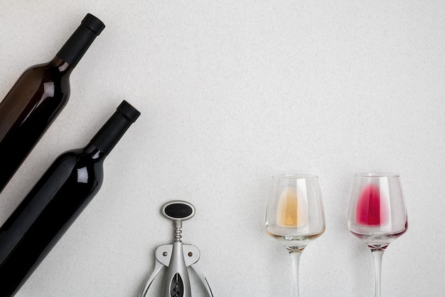 Bicchieri e bottiglie di vino rosso e bianco su sfondo bianco dalla vista dall'alto
