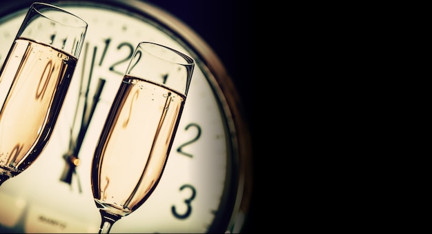 Glasses of champagne on clock background
