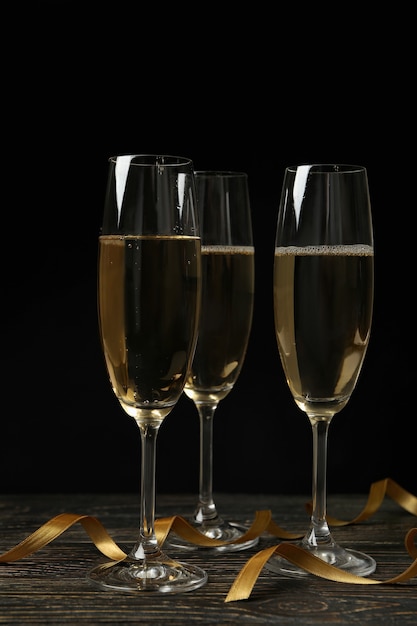 Glasses of champagne and curly ribbons on wooden table