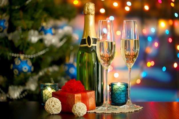 Glasses of champagne and gifts on bright background