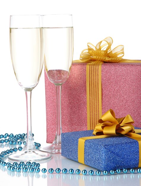 Glasses of champagne with gift boxes isolated on white