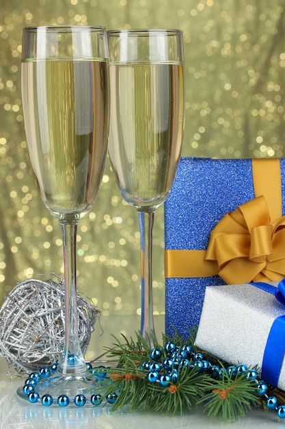 Glasses of champagne with gift boxes on shiny background