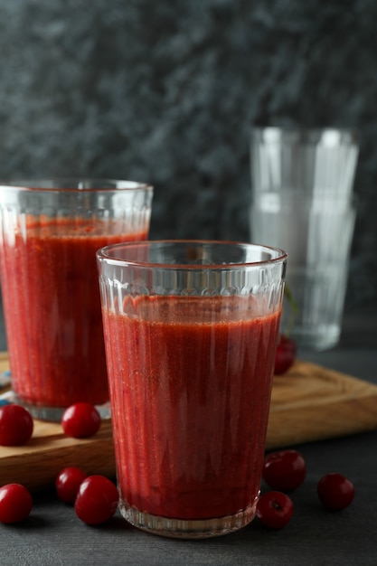 Glasses of cherry smoothie and ingredients on dark textured table