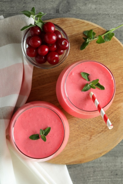 Glasses of cherry smoothie and ingredients on gray textured table