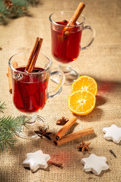 Glasses of Christmas mulled wine with spices orange and cookies on sackcloth