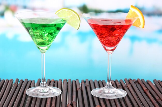 Glasses of cocktails on table near pool