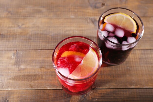 Glasses of cold berry cocktail on wooden background