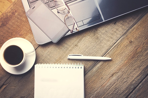 Photo glasses on computer, cup of coffee and paper on wooden table