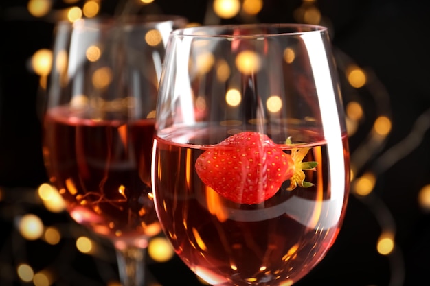 Glasses of delicious strawberry wine against defocused lights