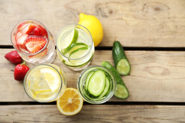 Glasses of different home made freshness healthy vitaminfortified water on wooden table