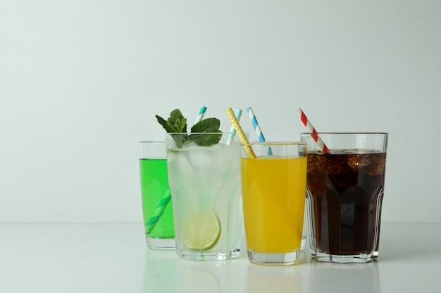 Glasses of different soda on white surface