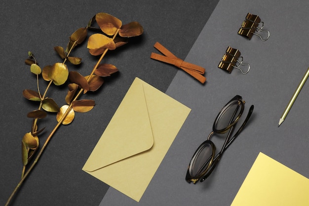 Glasses, envelope and gold branch on dark background