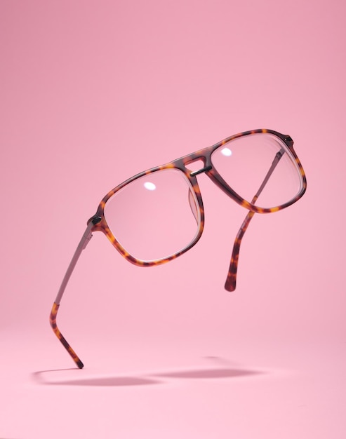 Glasses float in air touching pink surface Minimal retrostlyle