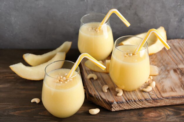 Glasses of fresh melon smoothie on wooden table